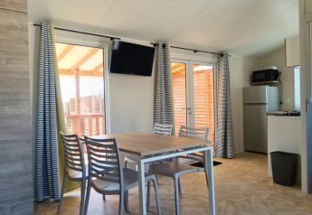 Dining area and kitchenette inside a Premium mobile home at Campsite Les Tamaris in France, modern decor.