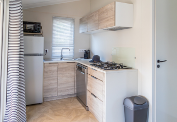 Modern kitchenette in a Premium mobile home at Campsite Les Tamaris, France, with stove and fridge.