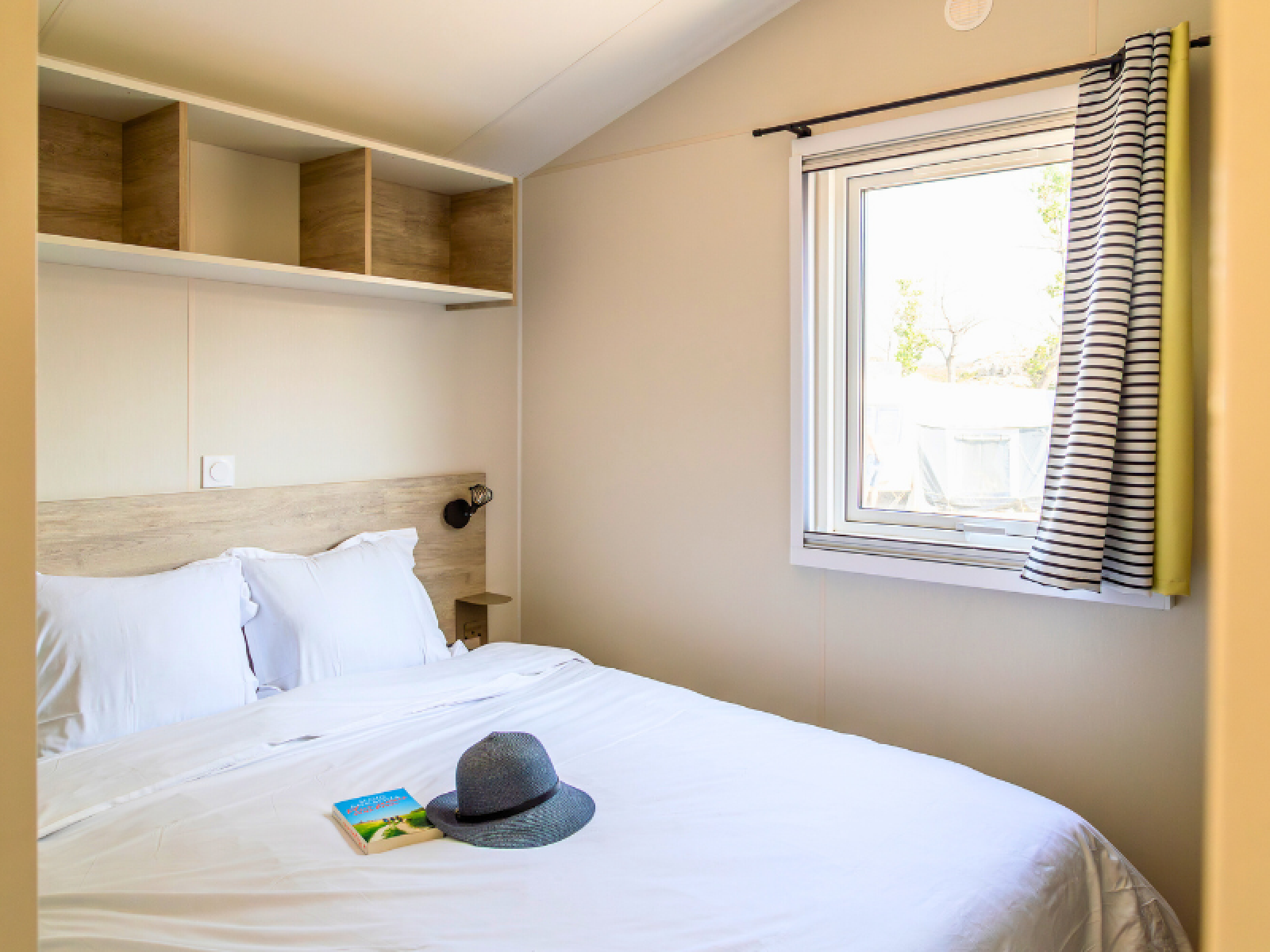 Lichte slaapkamer in Premium stacaravan op Camping Les Tamaris in Frankrijk, met tweepersoonsbed en raam.