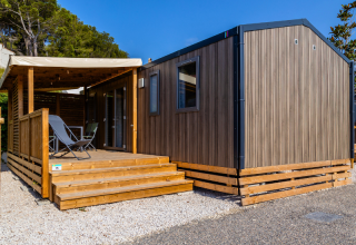 Casa móvil premium en el camping Les Tamaris en Francia con terraza de madera y sillas al aire libre.