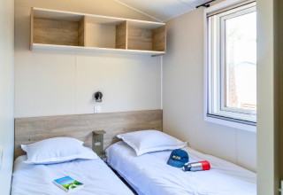 Bedroom in a Premium mobile home at Campsite Les Tamaris, France, featuring twin beds and a window.
