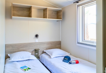 Bedroom in a Premium mobile home at Campsite Les Tamaris, France, featuring twin beds and a window.