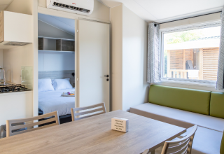 Interior of a Premium mobile home at Campsite Les Tamaris in France, showing dining area and bedroom.