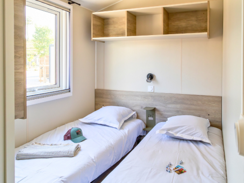 Interior view of Premium mobile home with two single beds at Campsite Les Tamaris in France.