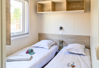 Interior view of Premium mobile home with two single beds at Campsite Les Tamaris in France.