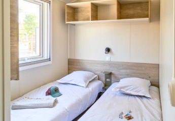 Vista interior de casa móvil Premium con dos camas individuales en el Camping Les Tamaris en Francia.