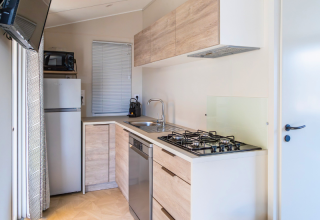 Modern kitchen in a Premium mobile home at Campsite Les Tamaris, featuring fridge, stove, and dishwasher.