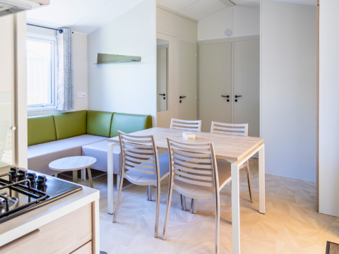 Interior of Premium mobile home at Campsite Les Tamaris in France, featuring dining table and green sofa.