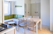 Interior of Premium mobile home at Campsite Les Tamaris in France, featuring dining table and green sofa.