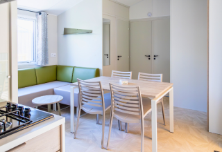 Interior of Premium mobile home at Campsite Les Tamaris in France, featuring dining table and green sofa.