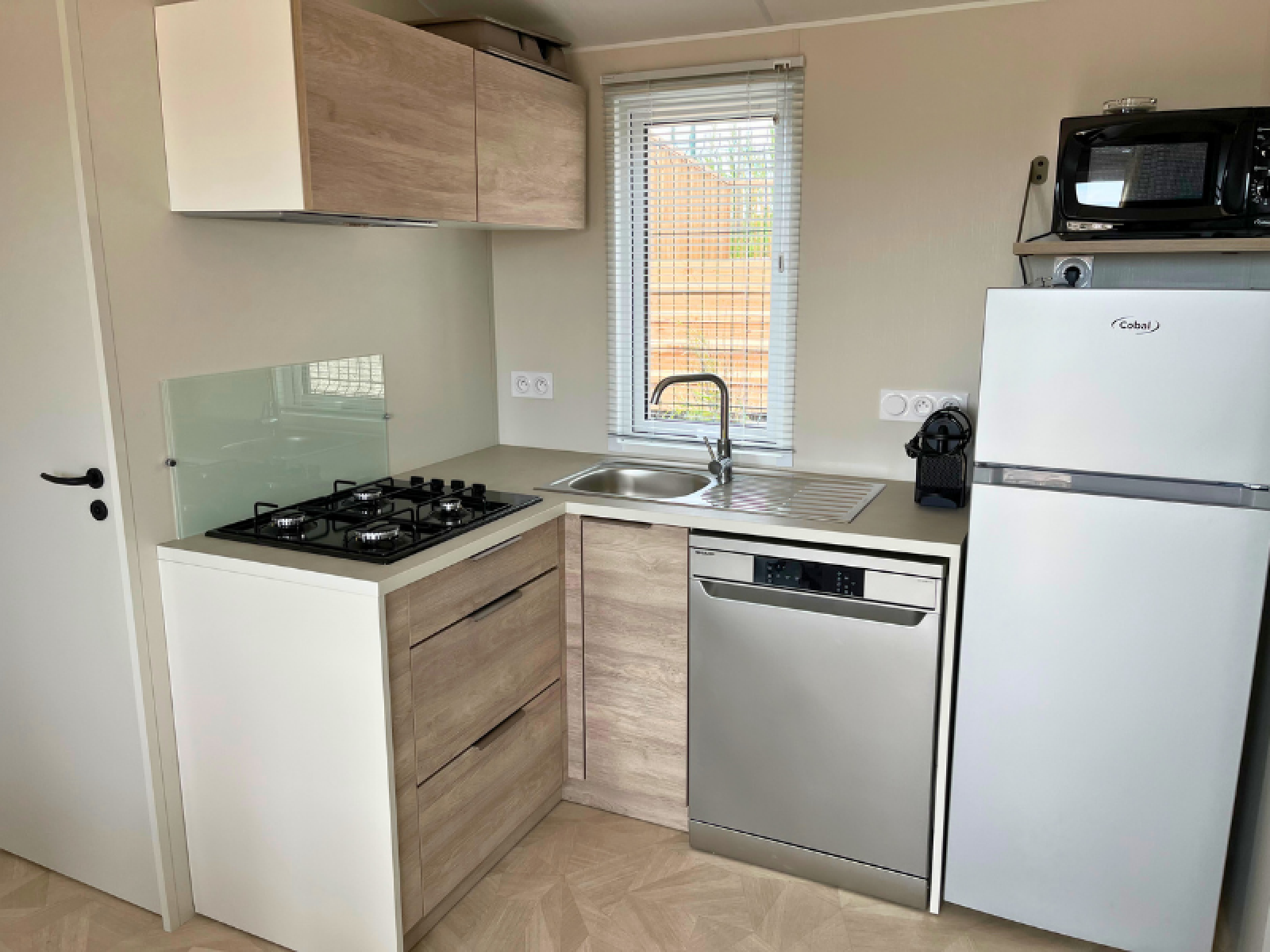 Moderne keuken in Premium Mobile Home op Camping Les Tamaris, Frankrijk, met fornuis, spoelbak en vaatwasser.