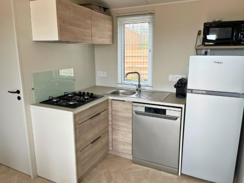 Moderne Küche im Premium Mobile Home auf Camping Les Tamaris, Frankreich, mit Herd, Spüle und Geräten.