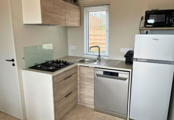 Cocina moderna en Premium Mobile Home del camping Les Tamaris, Francia, con estufa, fregadero y electrodomésticos.