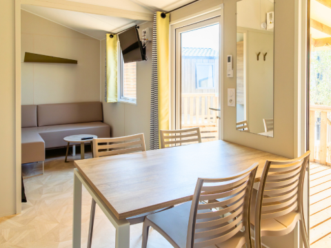 Interior view of Premium Mobile Home at Campsite Les Tamaris in France with dining table and sofa.