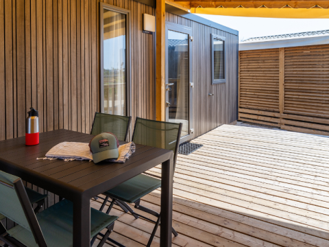 Terrasse des Premium Mobile Home auf dem Campingplatz Les Tamaris, mit Tisch, Stühlen und Holzverkleidung.