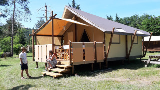 Deux personnes devant une tente safari appelée «Jungle Lodge» au camping Ushuaïa Villages Le Viaduc en France.