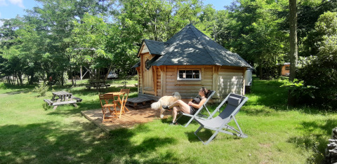 Une personne se détend devant une kota finlandaise au camping Ushuaïa Villages Le Viaduc en France.