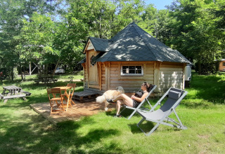 Une personne se détend devant une kota finlandaise au camping Ushuaïa Villages Le Viaduc en France.