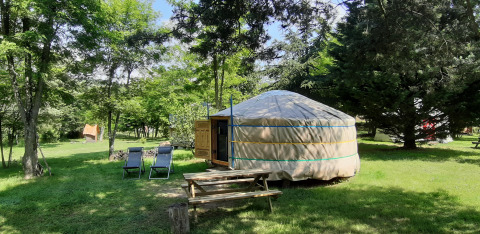 Una yurta tradizionale con tavolo da picnic e sdraio all’aperto al campeggio Ushuaïa Villages Le Viaduc.