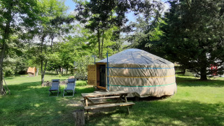 Een traditionele yurt met picknicktafel en ligstoelen op het gras bij Ushuaïa Villages Le Viaduc in Frankrijk.