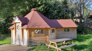 Finnische Kota-Lodge am Campingplatz Ushuaïa Villages Le Viaduc in Frankreich, umgeben von Natur.
