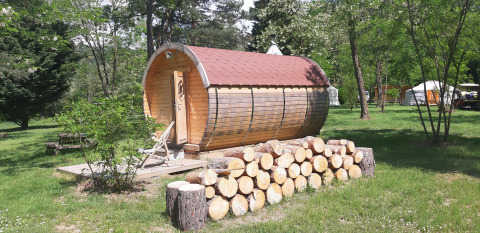 Wooden cabin and firewood stack at Ushuaïa Villages Le Viaduc campsite in Auvergne-Rhône-Alpes, France.