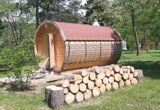 Wooden cabin and firewood stack at Ushuaïa Villages Le Viaduc campsite in Auvergne-Rhône-Alpes, France.