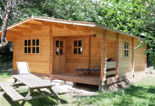 Una baita in legno al campeggio Ushuaïa Villages Le Viaduc, circondata da alberi e tavolo da picnic davanti.