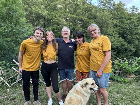 Five smiling people and a dog stand outdoors at Ushuaïa Villages Le Viaduc holiday park in Auvergne-Rhône-Alpes.