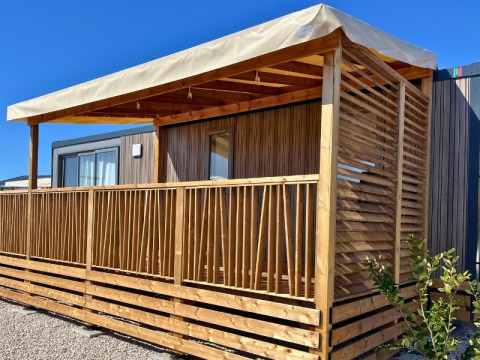 Vista esterna del Premium Mobile Home 'Large' con veranda in legno al Campeggio Les Tamaris in Francia.