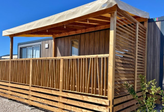 Vista esterna del Premium Mobile Home 'Large' con veranda in legno al Campeggio Les Tamaris in Francia.