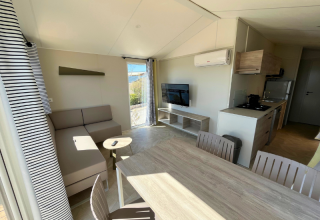 Soggiorno della Premium Mobile Home «Large» al campeggio Les Tamaris in Francia con divano e cucina.