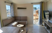 Modern living room of Premium Mobile Home 'Large' at Campsite Les Tamaris with sofa, TV, and table.