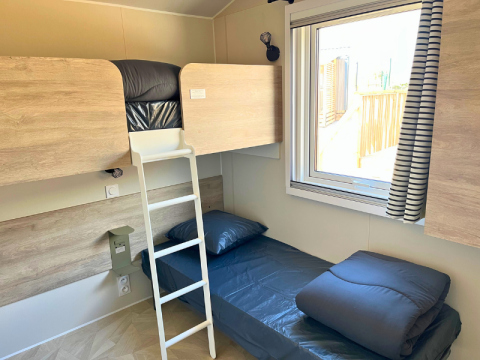 Camera con letto a castello e singolo nel Premium Mobile Home «Large» al Campeggio Les Tamaris, Francia.