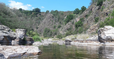 View of river and rocky cliffs at Ushuaïa Villages Le Viaduc campsite, Auvergne-Rhône-Alpes, France.