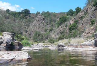 View of river and rocky cliffs at Ushuaïa Villages Le Viaduc campsite, Auvergne-Rhône-Alpes, France.