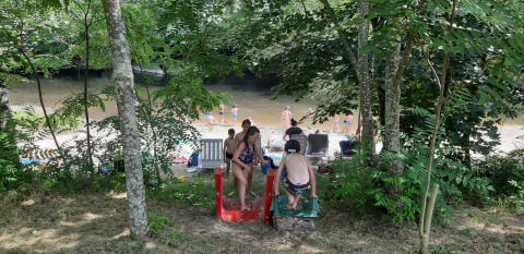 Children play on a slide near a riverside beach at Campsite Ushuaïa Villages Le Viaduc in France.