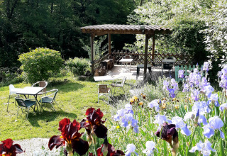 Garden scene with irises, outdoor seating and covered pergola at Ushuaïa Villages Le Viaduc in France.