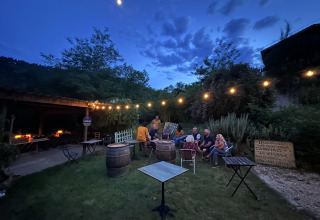 Evening at Ushuaïa Villages Le Viaduc campsite, people gathered outdoors under string lights in the garden.