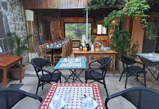 Zona pranzo all’aperto apparecchiata al campeggio Ushuaïa Villages Le Viaduc in Auvergne-Rhône-Alpes, Francia.