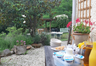 Outdoor breakfast with juice, yogurt, and flowers at Ushuaïa Villages Le Viaduc campsite in France.