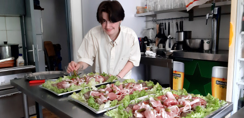 Una persona prepara piatti con insalata e affettati nella cucina di Ushuaïa Villages Le Viaduc, Francia.