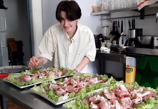 Una persona prepara piatti con insalata e affettati nella cucina di Ushuaïa Villages Le Viaduc, Francia.