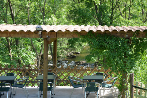 Terrazza all'aperto con tavoli e sedie al Campeggio Ushuaïa Villages Le Viaduc immersa nel verde.