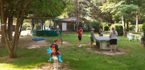 Children playing and adults playing table tennis on a green campsite at Ushuaïa Villages Le Viaduc holiday park.