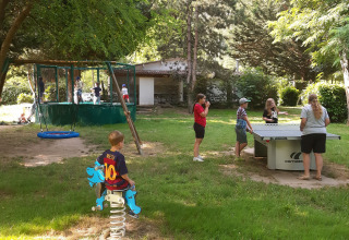 Bambini giocano e adulti giocano a ping pong in un campeggio verde a Ushuaïa Villages Le Viaduc in Francia.