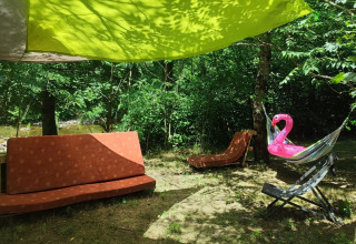 Campeggio all'aperto con divano, lettino e gonfiabile fenicottero rosa sotto un telo verde in Francia.