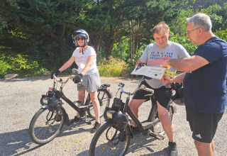 Due persone su biciclette d’epoca e una terza con una mappa godono il sole vicino ad Arlebosc, Francia.