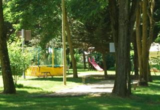 Campeggio verde con area giochi, scivolo e trampolino circondato da alberi in Alvernia-Rodano-Alpi, Francia.