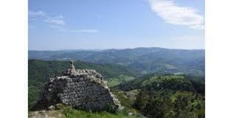 View of rolling hills and ancient stone ruins at Campsite Ushuaïa Villages Le Viaduc in Auvergne-Rhône-Alpes, France.